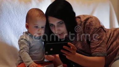一位年轻漂亮的母亲在智能<strong>手机</strong>屏幕上向儿子<strong>展示</strong>了一些东西，孩子看着智能<strong>手机</strong>。